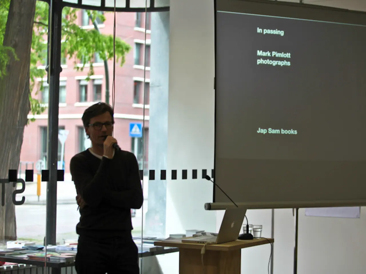 It is an office there is a person standing and speaking through a mic to his right side there is a...