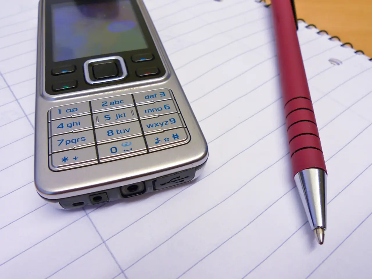 In this image we can see a mobile and a pen placed on a book.