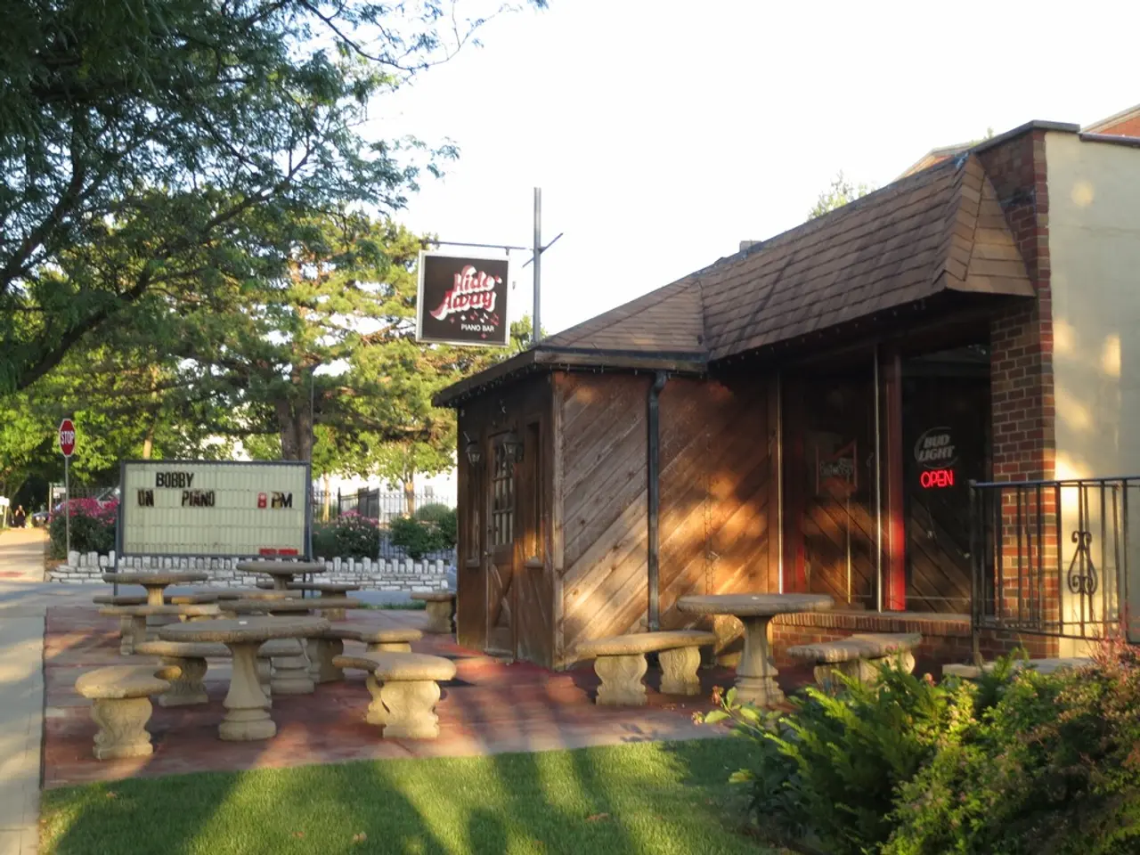 In this image we can see house, name board, benches, grass, plants, road, container, signboard,...