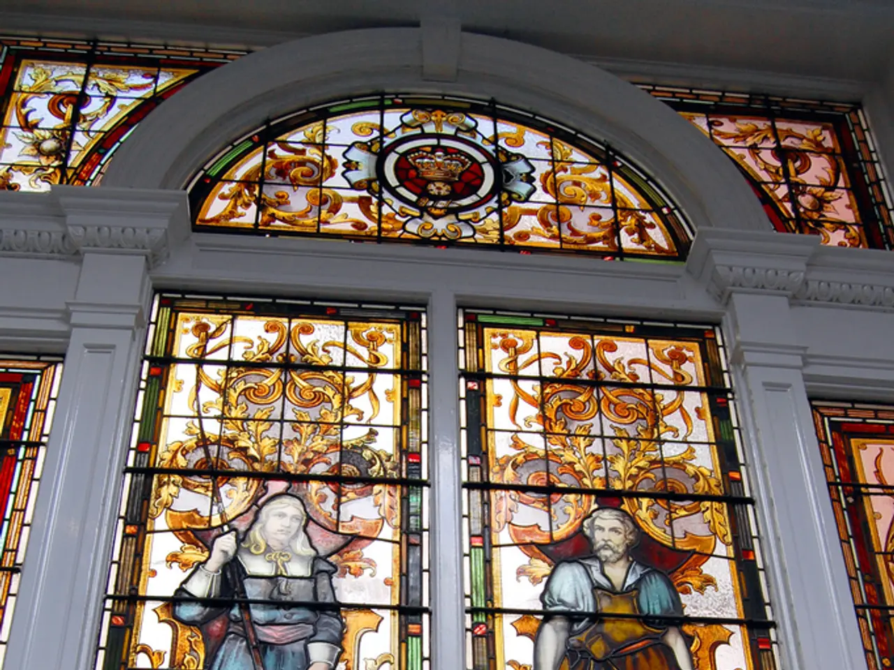 In the image there is a glass window on the wall with designs on it.
