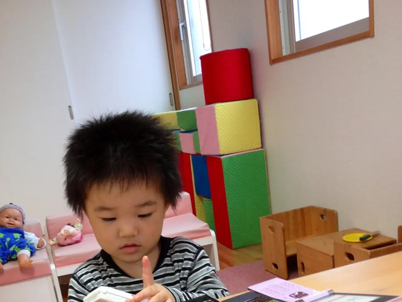 Here we can see a kid with a mobile phone in his hand and there are mobile phones placed on the...