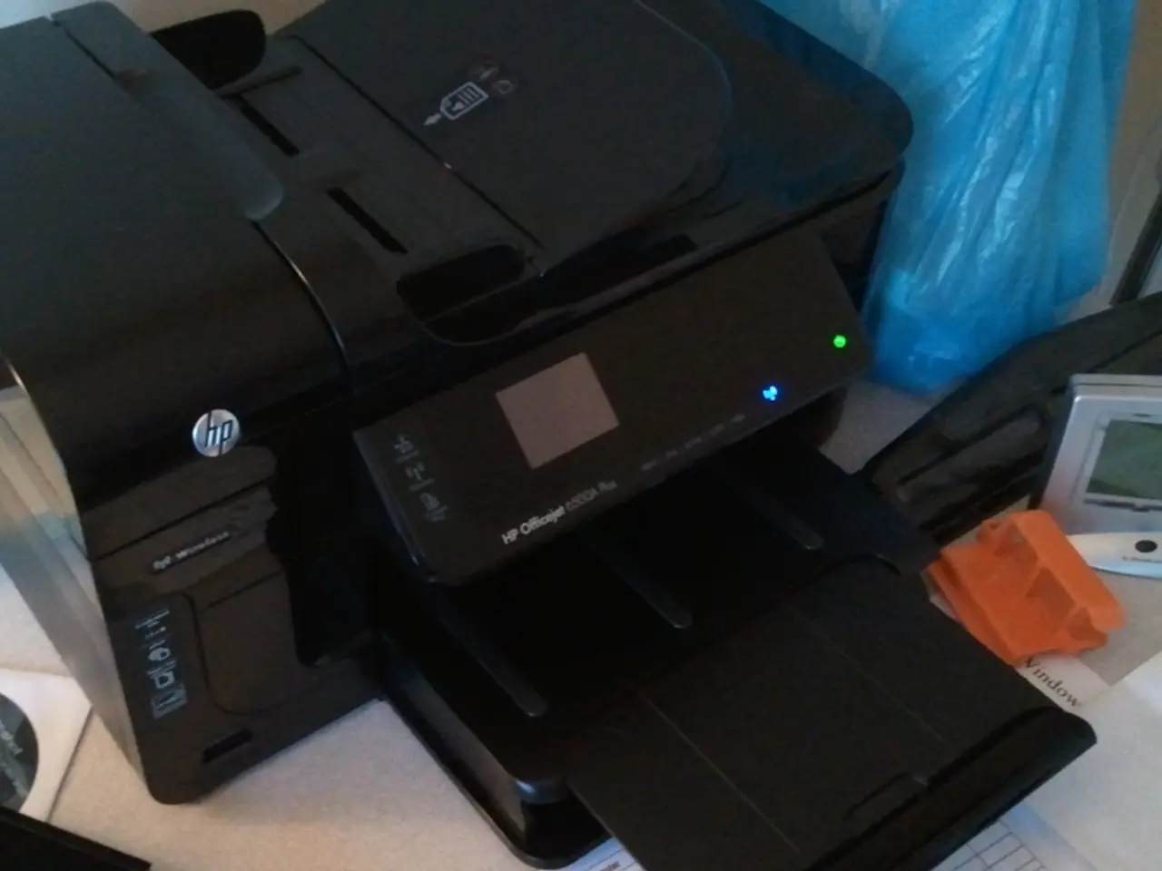On a table we can see a digital timer, hp printer machine, blue polythene cover, Compact disc in a...