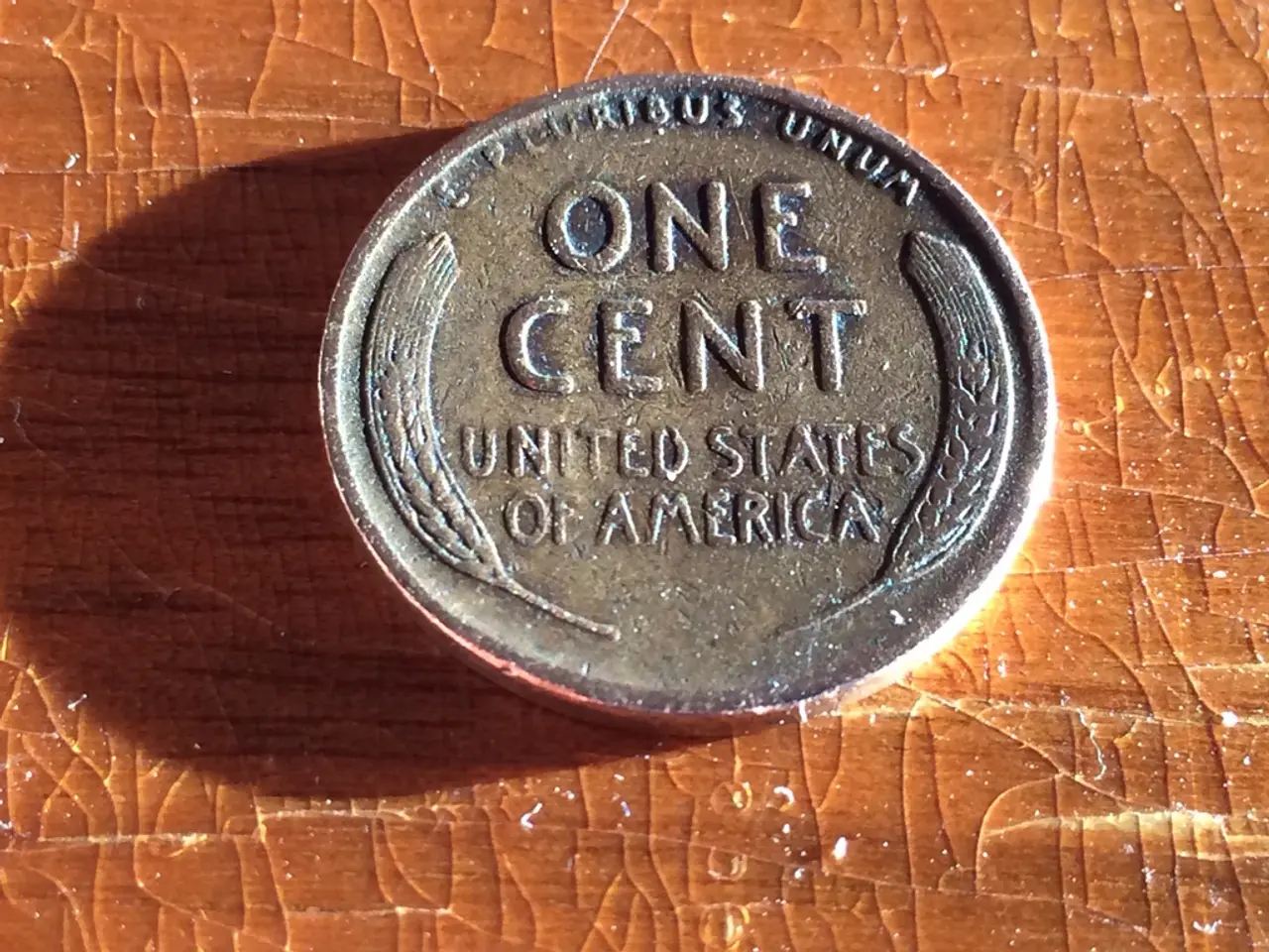 In this image I can see a coin and something is written on it. It is on the brown color board.