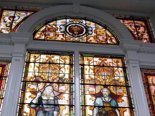 In the image there is a glass window on the wall with designs on it.