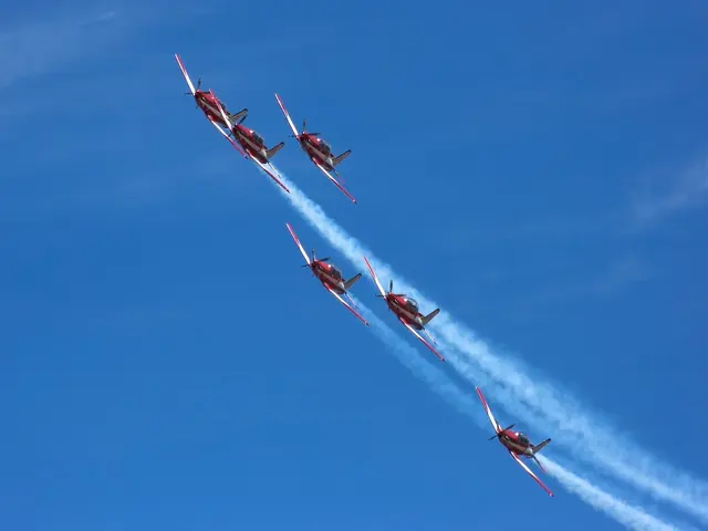In this image, I can see a group of aircrafts in the air. In the background, I can see smoke and...