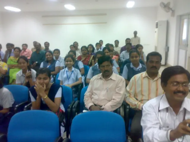 In this image there are group of persons sitting on a chair in a room and at the right side of the...