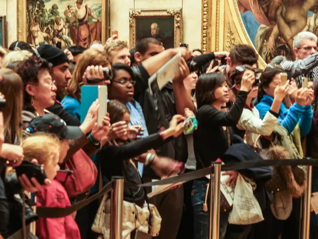 In the image there are many people standing and holding the cameras and mobiles in their hands. In...