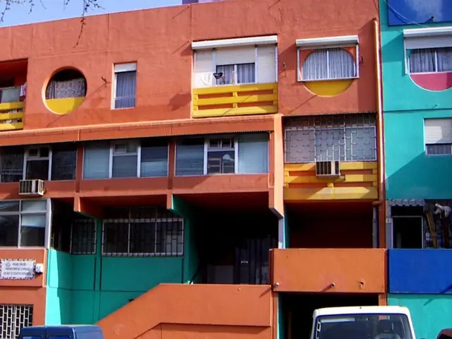 As we can see in the image there are buildings, fence, vehicles and a sky.