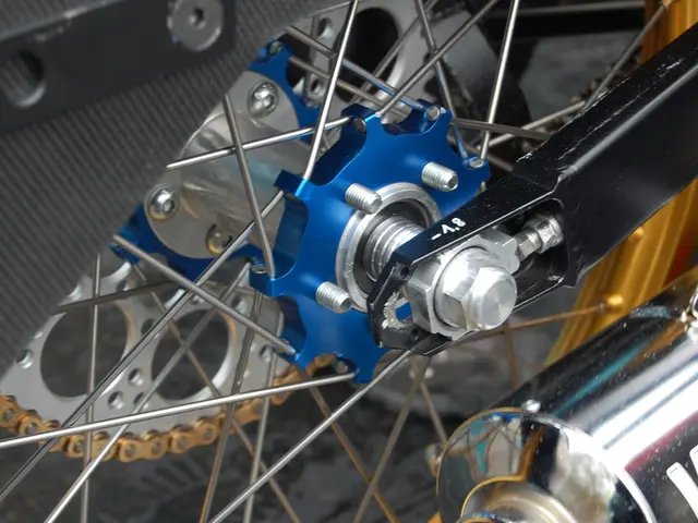 In this image we can see there is a motorbike wheel and a silencer.