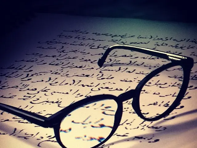In this image there is a paper having some text. Spectacles are kept on the paper.