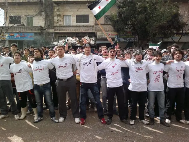 A group of people are standing and shouting, they wore white color t-shirts. Behind them there is a...