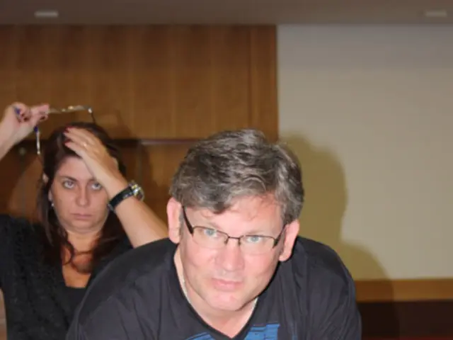 In the picture there is a man and a woman man is writing some thing on a paper with a pen on the...